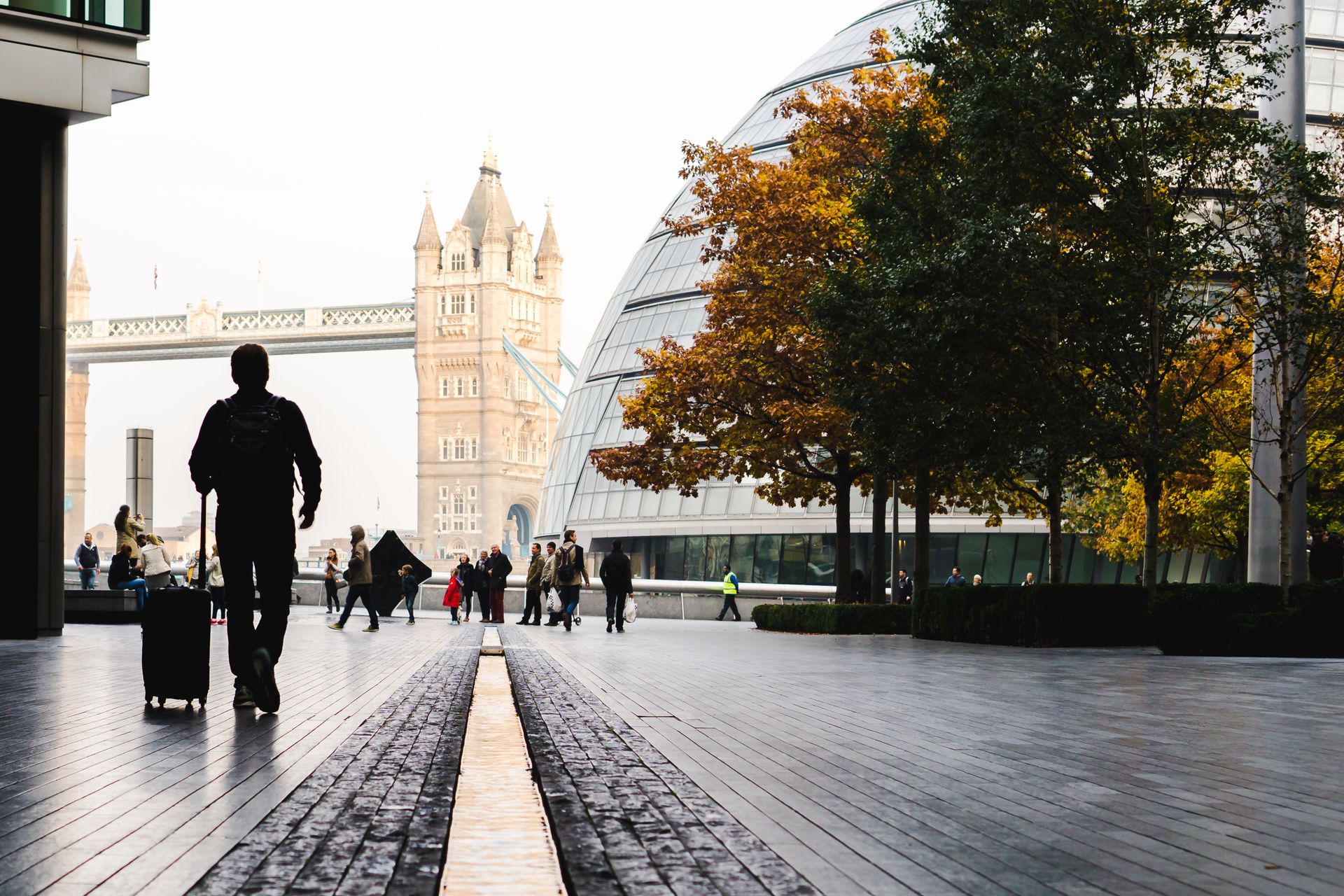 A traveler rolling a compact suitcase toward Tower Bridge in London