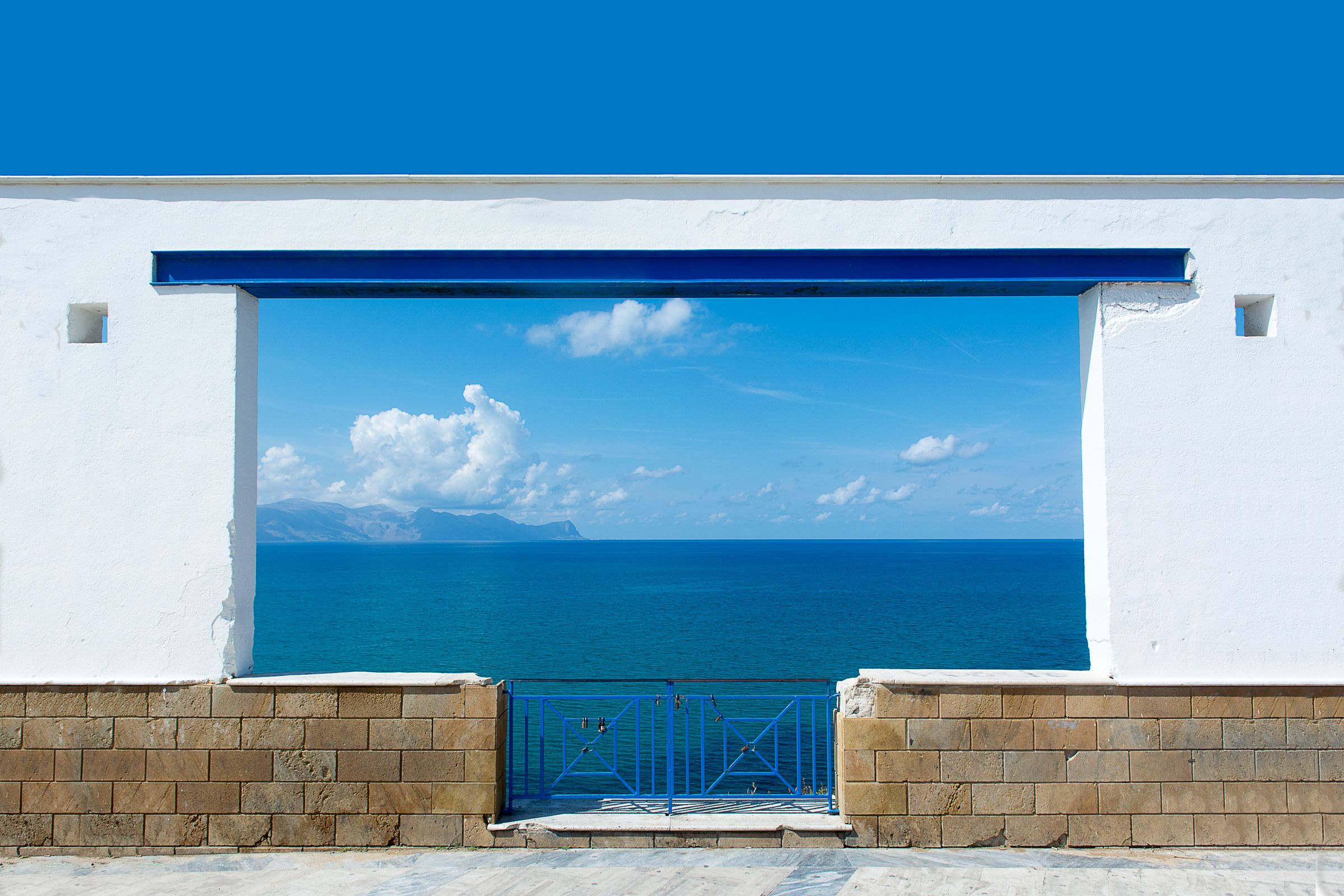 A quiet view of the sea through whitewashed architecture on a Greek island